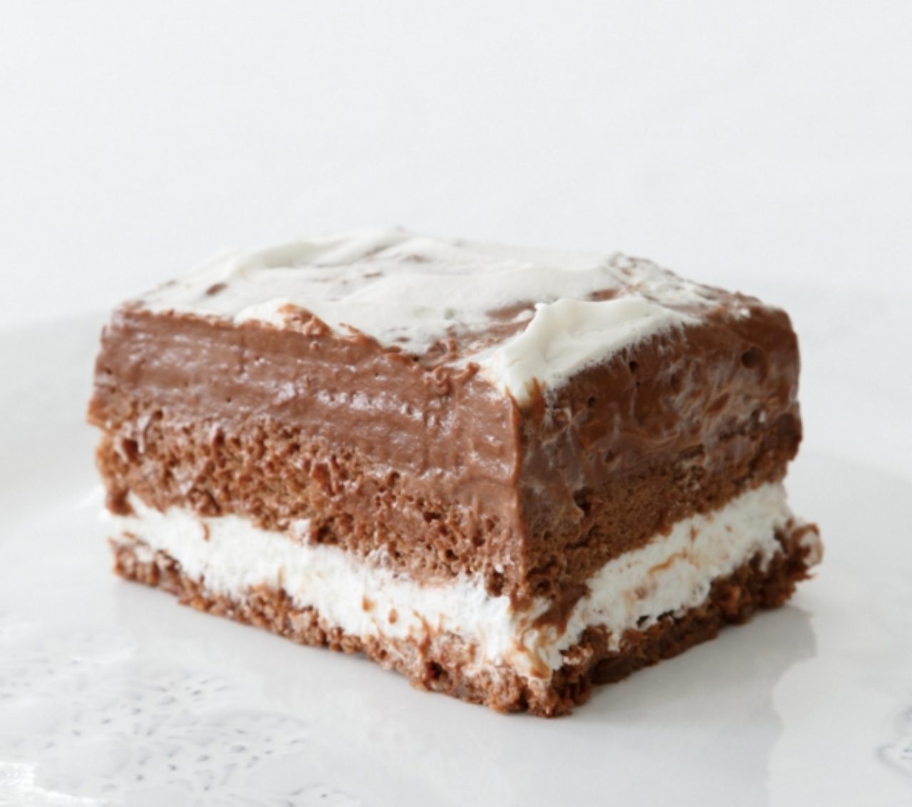 画像: デーツや木の実などの食感が愉しめるココア風味のタルト生地、2種類のチョコレートで作った濃厚でなめらかなチョコレートプディング、軽やかな味わいのホイップクリーム、カカオが香るココアスポンジを重ねて、4層仕立てのケーキに仕上げました。それぞれの色合いがわかる断面は、チョコレートケーキの深い味わいを演出しています。