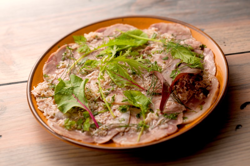 画像: 「ミュゾー(豚の頬と舌を豚の頭で巻き固めたハム)グリビッシュソース」 (2店舗で提供／Hemelミヤマスでは850円) ミュゾーとは豚の頭の皮で、豚の頬と舌を巻き固めたハムのこと。豚足やミミガー(豚の耳)に似た、クセのある独特の味にファンが多いです。作るのに手間がかかるのも特徴で、豚の頭を1週間塩水につけた後、3時間茹で、ここに茹でた豚の頬肉とタンを巻き込んで、頭の皮で固めます。ゼラチン質がたっぷりで、たまらないおいしさ。