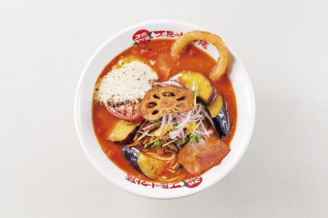 画像: ・商品名:『よくばり野菜のベジトマ麺』 ・販売価格:950円(税込) ・販売期間:2016年12月末予定(年末の営業時間は店舗より異なります。) ・商品特徴:数種類の野菜をふんだんに使用した12月限定のベジトマ麺です。レンコン、オニオンリング、さつま芋、アーリーレッド、カイワレ、江戸菜、茄子、ごぼう、トマトチーズをトッピング。 ごろっごろな野菜の食感、トマトにのせて炙ったゴルゴンゾーラがスープに溶け出しコクを与え、さらに自家製のレモンフレーバーEXVオイルでスッキリまとめた一杯です。