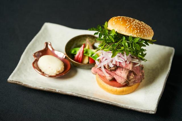 画像: 豪州産ローストビーフバーガー ¥2,480 (鉄板焼 開化屋) 1 時間以上じっくり鉄板火入れした極旨豪州 産サーロインのローストビーフが何枚も重なっ たボリューム満点の一品。ローストビーフのピン ク、オニオンの白、クレソンの緑、トマトの赤。 見た目にも爽やかで噛むほどに肉のうまみが 広がる、上品な味わいのバーガーです。