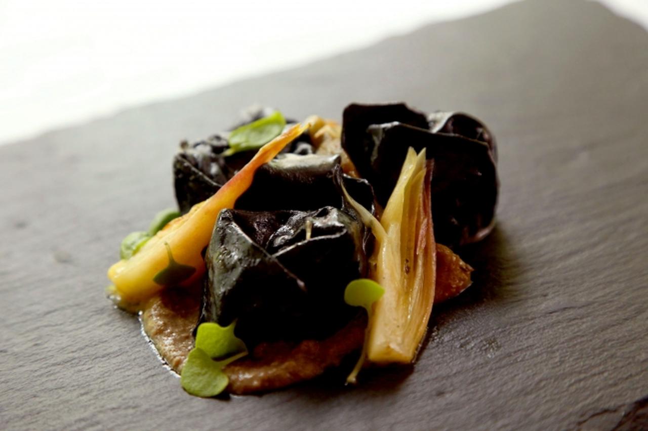 画像: 3．パスタ～ナチュラルブリッジ～ 岩魚のコンフィとジンジャーで炊き上げたジャガイモのリピエーノ　黒いトルテッリーニ ローストしたグリーンパプリカとミョウガを添えて　　　2,200円（税抜） ジンジャーとローリエで作ったハーブティーで炊き上げたジャガイモとコンフィにした岩魚をピューレ状にし、イカスミを練り込んだ黒いパスタの生地で包み込んだリピエーノ※。 “妖精の棲む洞窟の香り”を纏った、安らぎを感じさせながらも凛としたニュアンスを表現した一皿です。 使用ハーブ：ジンジャー、ローリエ ※リピエーノ＝詰めものをした料理の総称。