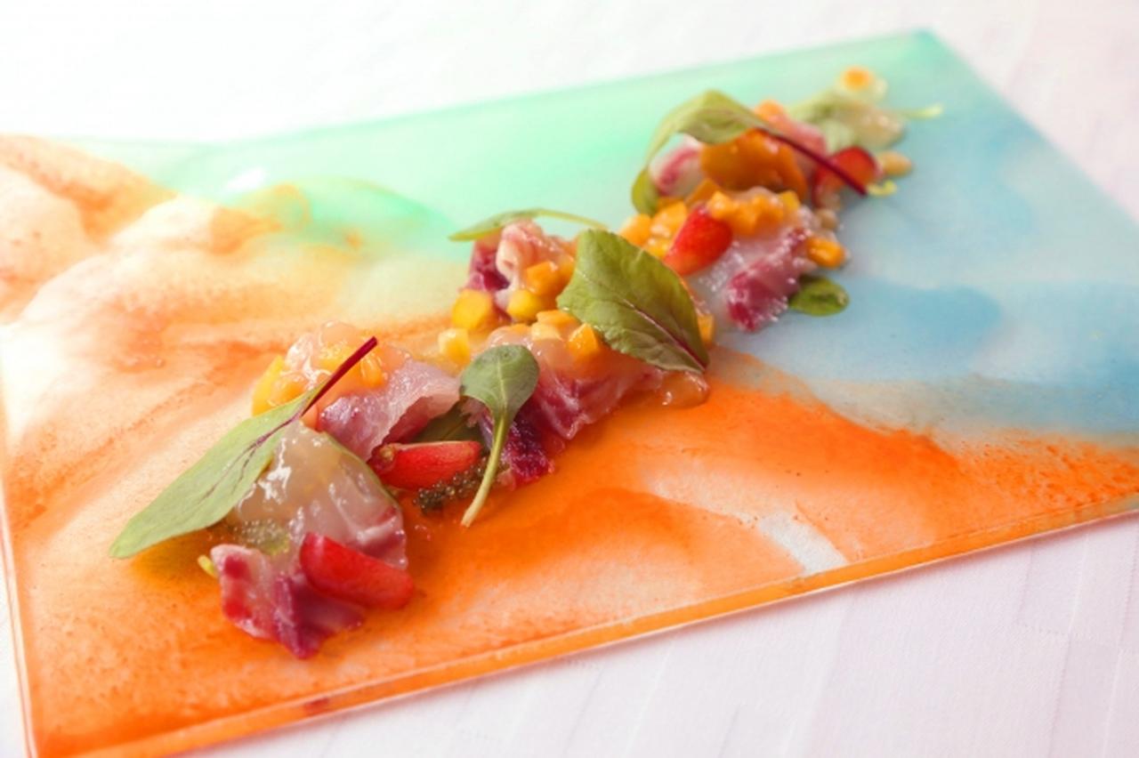 画像: 1．前菜～サーファーズパラダイス～ 伊佐木のカルパッチョ　レモングラスの香りを包み込ませたジュレ ルバーブのアクセント　トロピカルなイメージに　　　1,600円（税抜） 旬な伊佐木のカルパッチョを、アサリから取った出汁にレモングラス、レモンティートリー、リンデンウッドを使用したジュレと合わせ、さらにマンゴー、黄パプリカを加え、トロピカルなイメージと食感に仕上げました。白ワインでシンプルに炊き上げたルバーブを使用し、酸味のアクセントに。さくらんぼのフレッシュ感と海ぶどうの食感が心地よく、浮かび上がる“太陽の光を浴びた海岸線の情景”が、さわやかな気分にさせてくれます。 使用ハーブ：レモングラス、レモンティートリー、リンデンウッド
