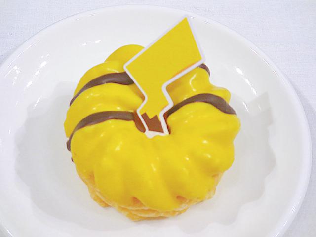 画像: ●ピカチュウのしっぽ カスタードをサンドしたフレンチクルーラーをバナナ風味のチョコでコーティング。 本体価格 180円(税抜) テイクアウト 194円(税込) イートイン 198円(税込) フレンチクルーラーをバナナ風味のチョコでコーティングし、中にはカスタードクリームが入っています。“ピカチュウのしっぽ”付きです。