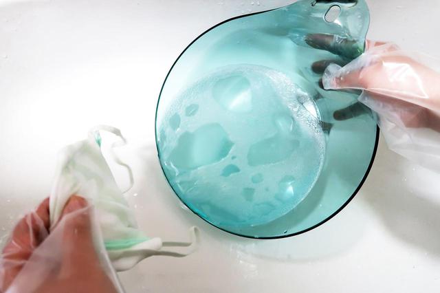 画像: 桶のオキシウォッシュ溶液を流します。漂白剤が飛び散らないようにゆっくり捨てます。