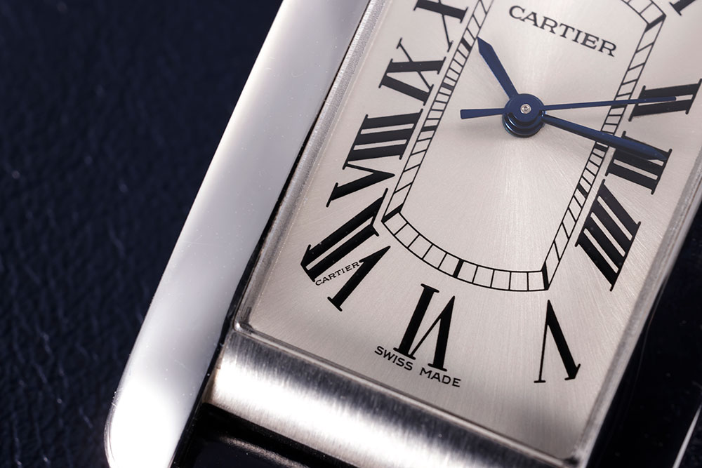 画像: 文字盤は伝統的なローマンインデックス。7時位置には「CARTIER」の隠し文字が入っている