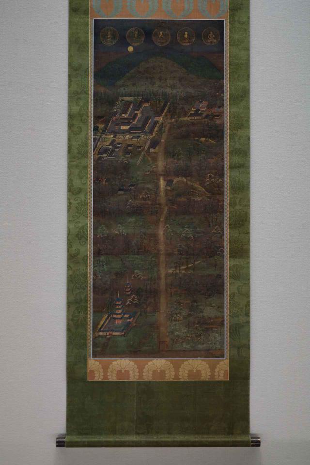 画像: 春日宮曼荼羅 鎌倉時代14世紀 根津美術館蔵 重要美術品 最上部・奥に春日山と、手前に御蓋山で、その麓の左に春日大社の本殿と本殿を取り囲む回廊など。右に春日若宮。中心の垂直の線が春日大社の参道で、右下に描かれている仏塔は神仏習合の時代にかつてあった春日大社の五重塔(今も奈良国立博物館の構内に礎石が残る)。 最上部は右端に若宮の本地仏・童形文殊菩薩。そして右から第一殿の本地仏・釈迦如来、第二殿・薬師如来、第三殿・地蔵菩薩、第四殿・千手観音菩薩