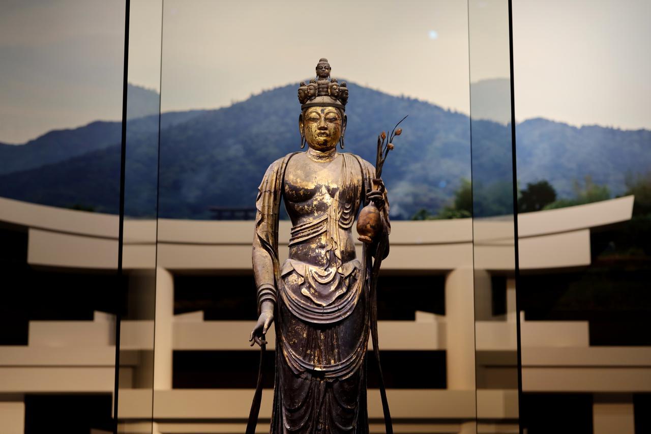 画像: 国宝 十一面観音菩薩立像 (部分) 奈良時代・8世紀 奈良・聖林寺蔵 背景には三輪山の写真と、大神神社の三ツ鳥居の再現