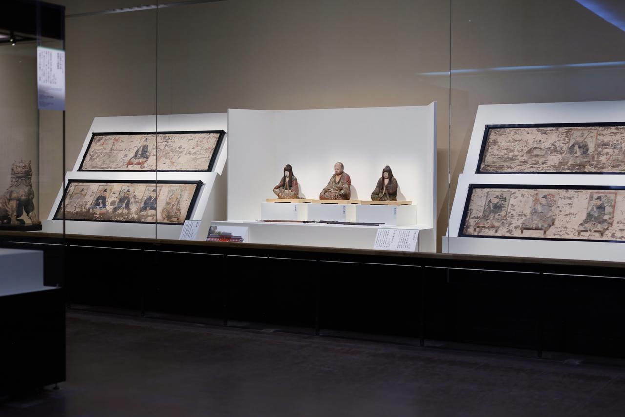 画像: 展示風景、かつての休ヶ岡八幡宮の信仰空間を再現。左右の板絵神像は重要文化財、鎌倉時代・永仁3年（1295)、奥の狛犬は鎌倉時代、13〜14世紀