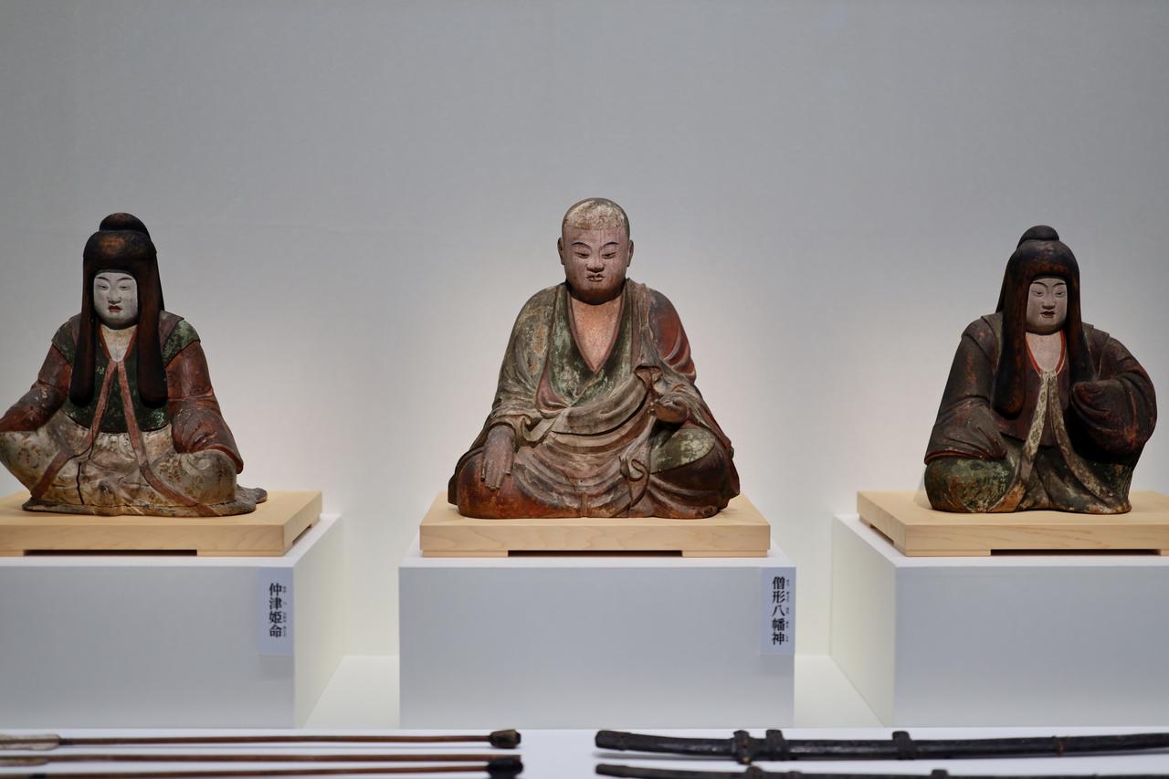 画像: 国宝 八幡三神坐像 平安時代・9世紀 奈良・薬師寺 八幡神の右に皇后の仲津姫命、右が神功皇后。手前に太刀と矢の古神宝。太刀の鞘には蒔絵で草花の文様が