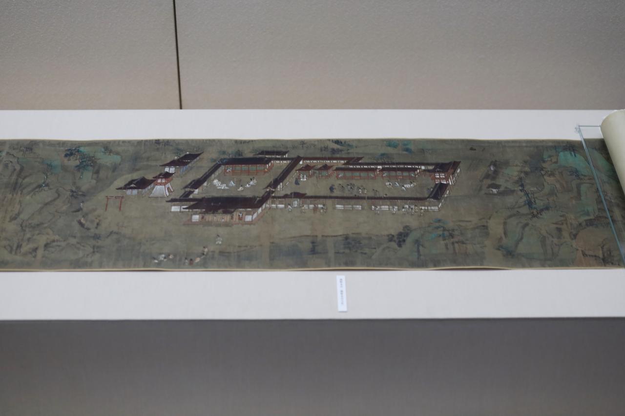 画像: 国宝 一遍聖絵 巻第三 法眼円伊筆 鎌倉時代・正安元年（1299) 神奈川・清浄光寺（遊行寺） 展示期間 5月20日〜6月15日 一遍上人が熊野に詣で、本宮で熊野権現の顕現に啓示を受ける場面。あえて大自然の風景の中に主人公を突き放したように本宮の社殿を風景の中に俯瞰した構図の中で、主人公の一遍は極小に、しかし緻密に描かれていて一目でそれと判る。