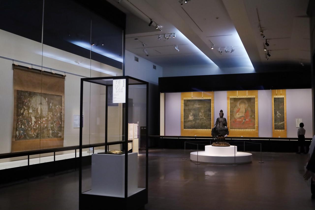 画像: 法華寺の阿弥陀三尊および童子図の前に、阿弥陀如来の分身であり救済の実行のための仮の姿ともみなされる観音菩薩（正確には尊格が未判別の菩薩半跏像、宝菩提院願徳寺）