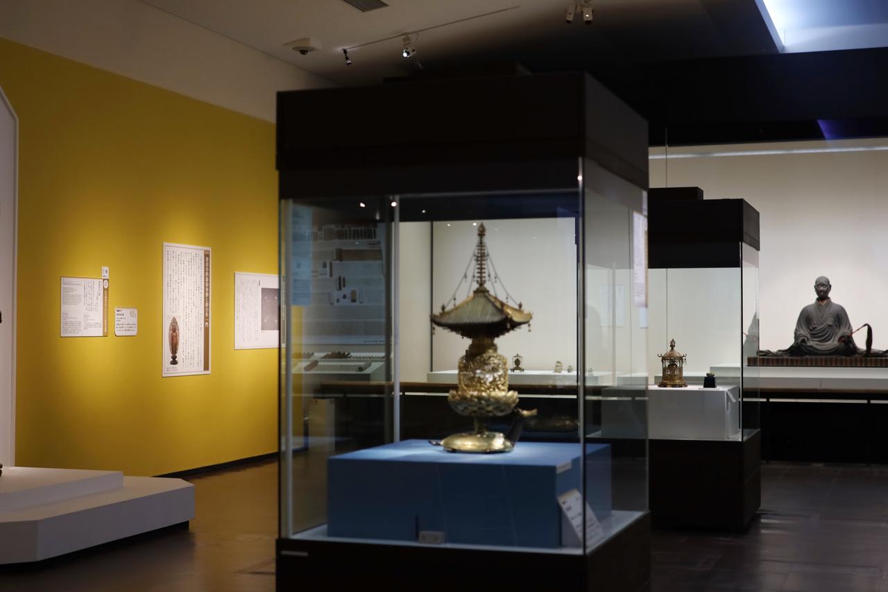 画像: 第三章・「釈迦を慕う」の後期展示風景。叡尊の分身像の前に釈迦の遺骨の断片を納めた舎利容器と、左端の白い台の上・画面すぐ外に国宝・清涼寺釈迦如来立像が。つまりこの空間の全体が、叡尊が様々な釈迦の姿を見ているように構成されている。