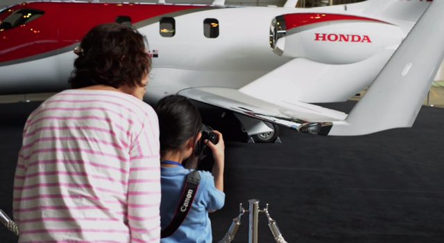 画像: ホンダ初の小型ジェットを撮影する幼い少女。彼女が抱えるカメラはキヤノン。 www.youtube.com