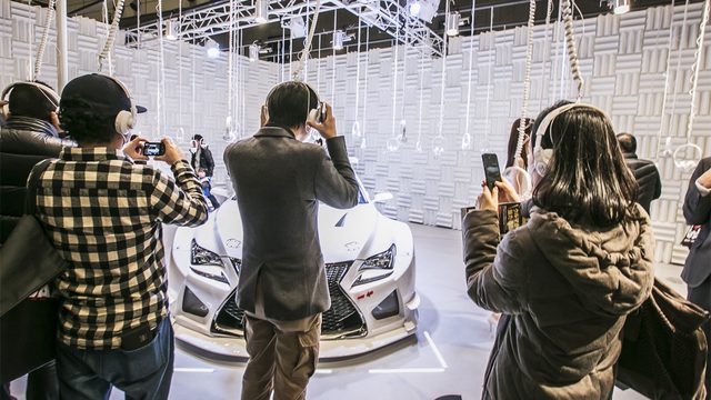 画像: ブースの天井から吊るされたヘッドフォンで視聴する来場者 lexus.jp