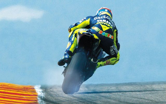 画像: 2005年のバレンティーノ・ロッシ(ヤマハ)の走り。激しいドリフトで後輪からスモークがたちこめています。 images.mcn.bauercdn.com
