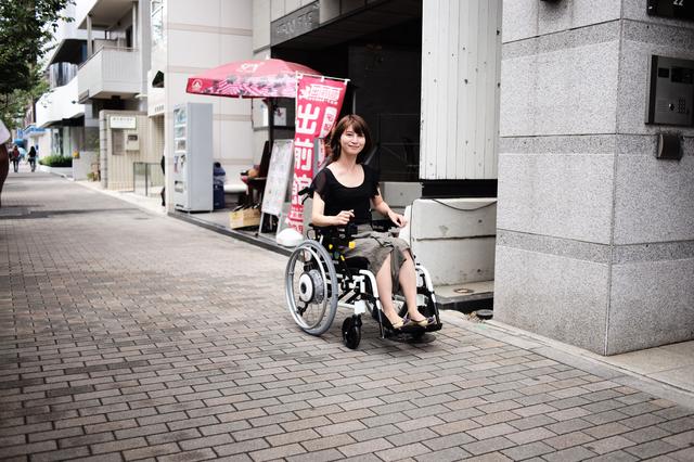 画像: 早足で歩く程度のスピードなので、怖くないし、すぐになれます。初めて乗ってもすぐ笑顔。 介護をする人が付き添いする場合は、背後から後ろのハンドルを握ります。。その場合も、速度を調整しつつ、電動によって、押すのではなく車いす自体を 自分が歩きやすい速度で動かすことができるのです。