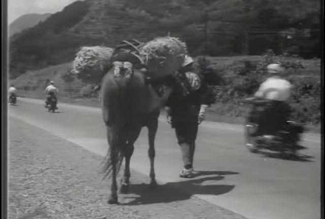 画像: 1950年代、荷馬のうしろを駆け抜けていくメグロのバイク。