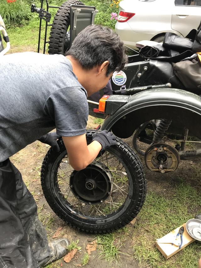 画像: 側車側のドラムブレーキの点検をする堀田さん。なお氏のウラルは、2013年型のキャブレター(ケーヒンCVK)モデルです。