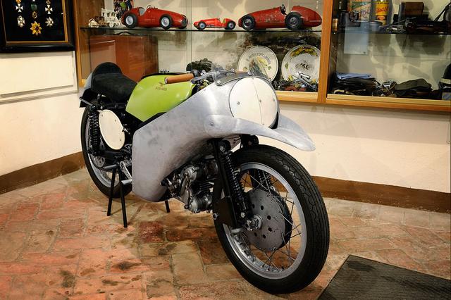 画像: 1954年の350ccクラスを制覇した、ファーガス・アンダーソンの350ビアルベロ(空冷単気筒DOHC2バルブ)。フロントフェンダーを兼ねたこのくちばしが、最初期のエアロ・デバイスと言えるのではないでしょうか? www.motorvalley.com