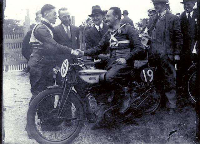 画像: 1932年、ノートン車上でウォルター・ハンドレーと握手をするスタンレー・ウッズ・ハンドレーの右の背広の人物が、"無敵艦隊"ことノートンワークスチームを率いたジョー・クレイグその人です。 www.vintagenorton.com