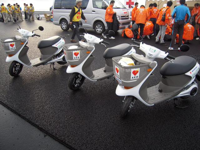画像: 2011年11月20日、「東日本復興支援ふじのくに新東名マラソン」に大会サポート車両として貸与されたe-Let’sの実証実験車。貸与された合計9台の内訳は、移動審判車3台、救護車を兼務するAED積載車3台(写真)、大会連絡車3台でした。 www.autoby.jp