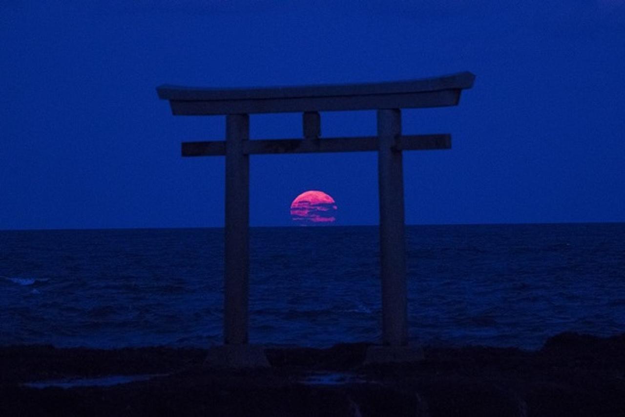 海から出てきた月が鳥居を通過神々しい大洗の「風景写真」に