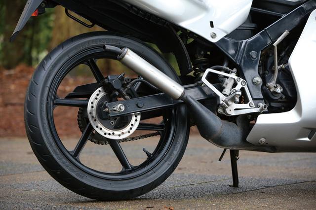 画像: リアがディスクブレーキなのもNS50Fとは違う部分。6本スポークのデザインはホンダスポーツバイク共通のデザイン。サイレンサーが黒じゃなくアルミ風なのは後期型の特徴である。