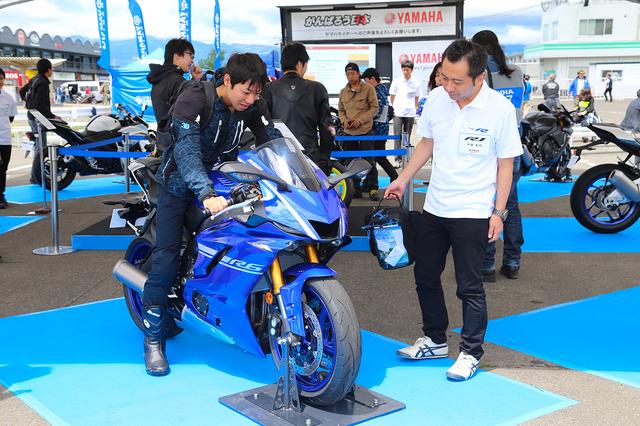 画像: 会場にはRシリーズの最新モデルが展示されており、壁面にはRシリーズヒストリーパネルも。白いポロシャツが開発陣スタッフの方達の目印で、参加者の皆さんとRシリーズを熱く語り合っている方が多かったです。