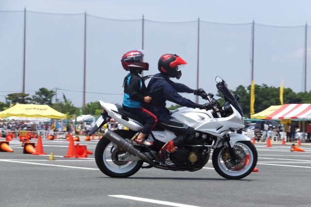 画像: ちびっこライダータンデム体験ではジムカーナ選手がちびっこを載せて走ります。 それぞれ無線で通じていて、お父さんが「もっとスピード出して!もっとスラローム走って!」なんてお願いをしてくるそうです。(^^) もちろんライダーは後ろのお子様優先で、怖がらないよう注意します。