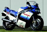 画像: ■SUZUKI GSX-R750 1985年3月発売 GSX-R750のコンセプトは、83年のRG250Γから続く、スズキのレーサーレプリカシリーズの延長線上にあった。小さく軽い車体に、高出力のエンジンを搭載する…当時の世界GPで、7年連続メーカータイトルを獲得したスズキのGPマシン作りのセオリーのひとつでもあったのだ。乾燥重量は当時の400ccクラス並みの180kg、出力は100PSを目指し、当時すでに常識となり始めていた水冷エンジンを敢えて避け、それまでの空冷システムの進化バージョンといえる「油冷(SACS)」システムを考案。エンジンにウォータージャケットを設ける必要がなく、ラジエター、冷却水の分も軽量になるというアイディアで、エンジン単体重量から軽量化を目指していた。フレームには、スズキが先鞭をつけ、その後に市販スーパースポーツの常識となったアルミフレームを使用し、前人未到の乾燥重量179kgを達成。83年のGSX750E4の210kgから、実に31kgもの軽量化だった。ライバルと同じ土俵を良しとせず、新しい世界や技術を切り拓く、スズキのエンジニア魂がこもったニューモデルだった。 ●油冷4ストDOHC4バルブ並列4気筒●749cc●77PS/9500rpm●6.4kgm/8000rpm●179kg●110/80-18・140/70-18●78万円