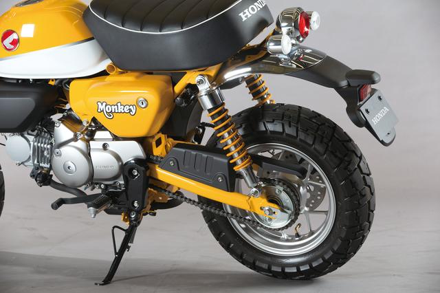 画像: スプリングを車体色と同じイエローにしたリアサスペンション。細いスイングアームや大きいチェーンガードもオリジナルを踏襲したもの。ヘルメットホルダーも備わっている。