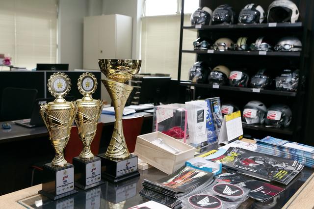 画像: 店長の田中教世さんは2016年まで全日本モトクロス選手権の最高峰カテゴリーに22年間参戦してきたオフロードのエキスパート。現役引退後もアジア選手権モトクロスや全日本エンデューロで好成績を収めており、店内には歴戦のトロフィーが飾られていました。