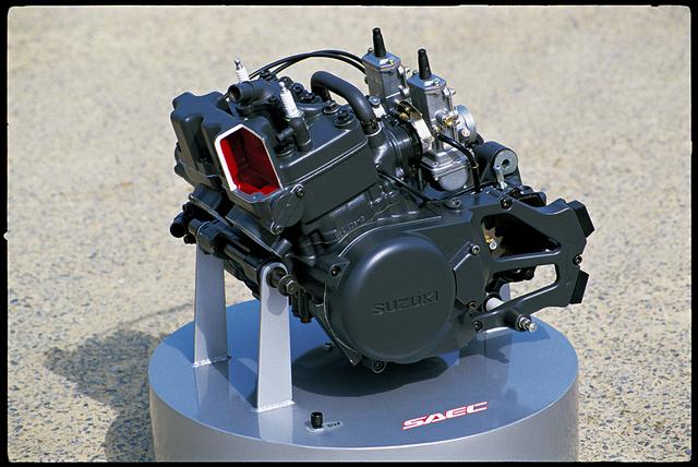 画像: 3代目となる1985年モデルでフルモデルチェンジし型はGJ21Bへと進化したRG250Γ。電子制御式排気デバイス=SAEC(Suzuki Automatic Exhaust Control)と多段膨張型マフラーとの相乗効果で馬力の谷間を解消し、低中回転域から高回転域までトルクフルで切れ味鋭い吹け上がりを実現した。 偏心カムを採用したE-フルフローター・サスペンションは一段と優れたプログレッシブ特性を発揮。