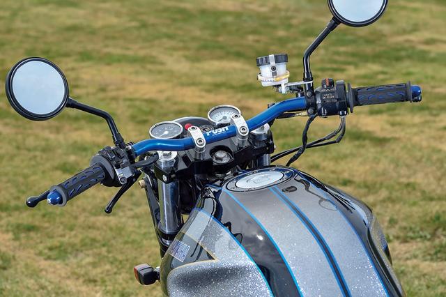 画像: ハンドルバーはポッシュ製で、車体色変更に合わせてブルーに変更する。バーエンド、グリップも同様。メーターも一般的な2眼式から小径なものに換装してフラットな配置に変えている。左スイッチボックス下に見えるレバーはSRならではのキックスタートのデコンプ用だ。