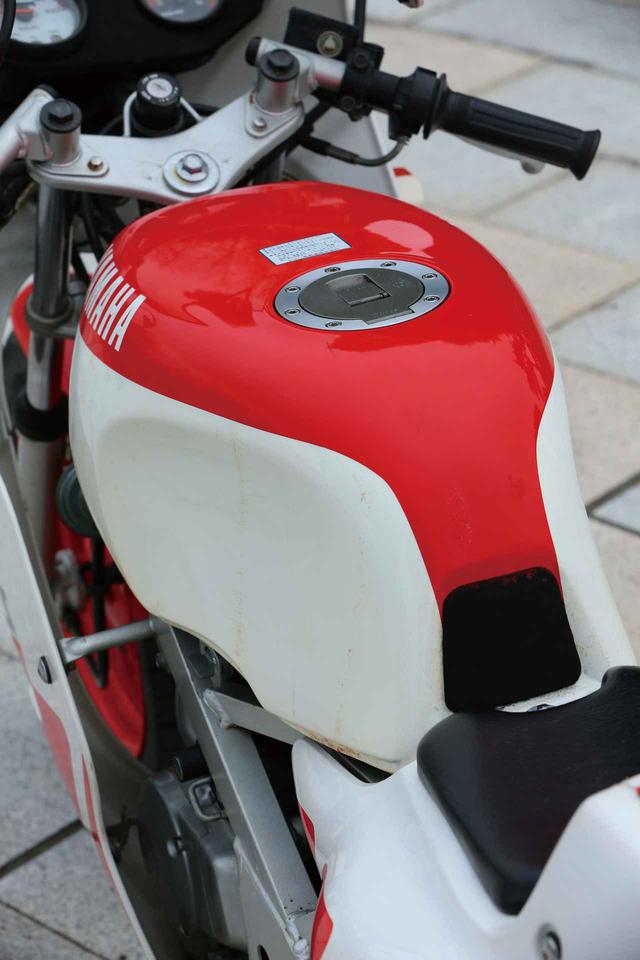 画像: 燃料タンクは8L。2ストオイルのタンク容量は0.7L。メインフレーム中央部分にヘルメットホルダーを装備している。この個体は回転計を装備したYSR80のメーターになっていた。