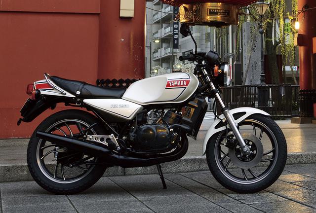 画像: ヤマハ RZ250 82年のバイクブームは突然訪れたわけではない。中型免許がメインの若いライダーを惹き付けるニューマシンが、80年から続々と登場していた。その1台が2ストを復権させ、その後の250レプリカブームの嚆矢となったRZ250だ。そのデビューは、それまでバイクに興味のない者をライダーに誘うほどのインパクトを持っていた。 【RZ250主要諸元】●エンジン形式:水冷2スト・ピストンリードバルブ並列2気筒●総排気量:247cc●最高出力:35PS/8500rpm●最大トルク:3.0kg-m/8000rpm●乾燥重量:139kg●燃料タンク容量:16ℓ●タイヤサイズ前・後:3.00-18・3.50-18●発売年月:1980年8月●発売当時の新車価格:35万4000円
