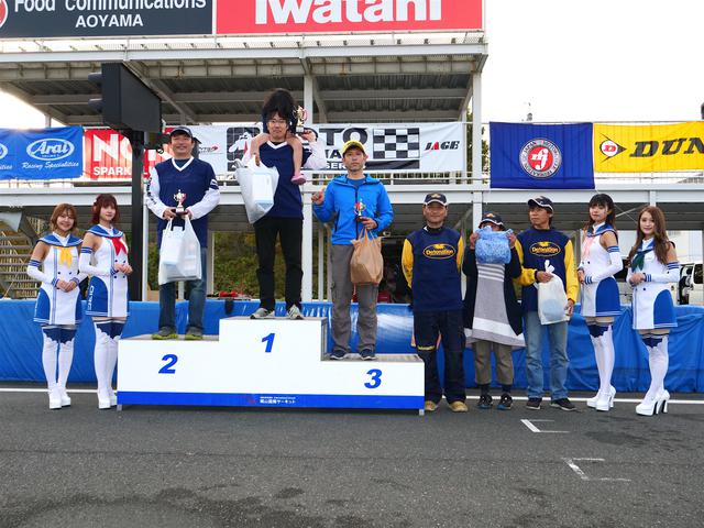 画像: 左から2位・池田秀一選手、1位・冨永崇史選手、3位・廣瀬 章選手、4位・作田隆義選手、5位・大越研二選手、6位・中嶋秀和選手。表彰式には岡山国際サーキットのサーキットクイーンも華を添えてくれた。