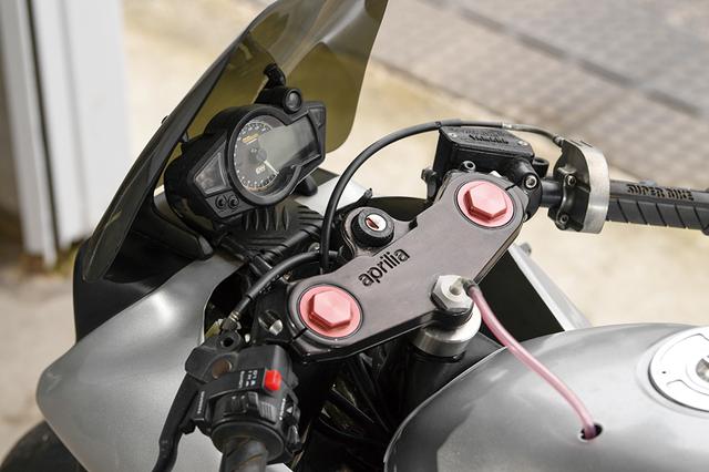 画像: フロントフォークまわりに合わせて、ステムまわりもアプリリアから流用したという。液晶パネル+アナログ回転計ワンボディのメーターはSP武川製を装着。
