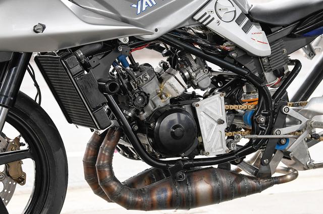 画像: エンジンはRZ250Rの並列2気筒をピストンリードバルブからセミクランクケースリードバルブ式に加工済み。シリンダーも補助排気ポートを追加工、これに応じてピストンはNSR250RのMC21用加工流用している。点火系はOSR・CDI電撃スペシャルで、キャブレターにはケーヒン製PJ38ショートをチョイスした。