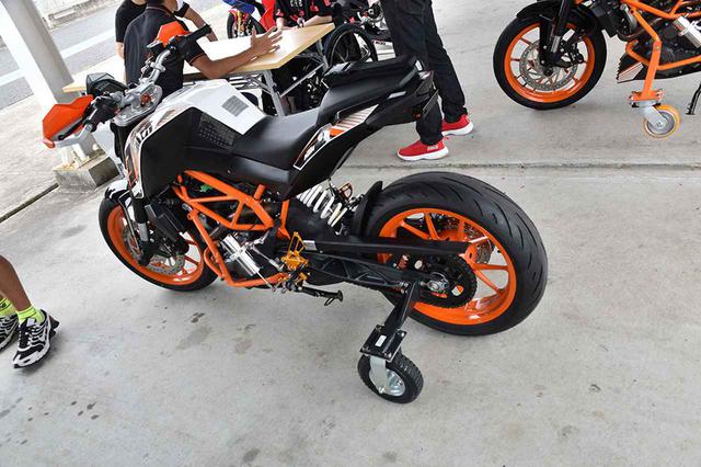 画像: サーキット内のパドックで練習走行をするため新たに投入された車両。下の既存の補助輪車両よりももう少し補助輪が強くサポートするタイプとなった。