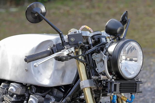 画像: 削り出しボディのミラーや超小型のLEDウインカーはドイツ・ハイサイダー製。ヘッドライトはステアリングヘッド部分から伸びた2枚のプレート型ステーでマウント、さらにヘッドライト下に伸びた丸パイプ下端にステーを作り、ウインカーをマウントしてある。