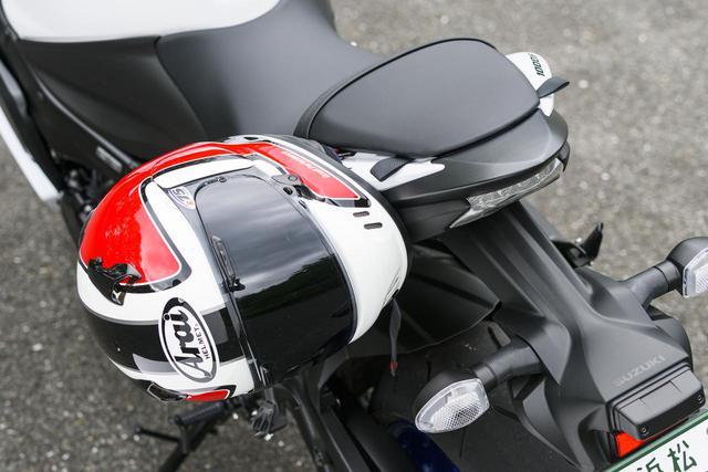 画像: タンデムシート裏にフックを設けたヘルメットホルダー。同じく荷かけフック用のフラップが収納されていて、タンデムステップ裏と併用して荷物積載やドローコードを使用。