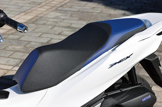 画像: シート形状はPCX/PCX160と同じだが、ブルー表皮をあしらいe:HEVの特別感を強調。サイドの車名バッジもブルーだ。
