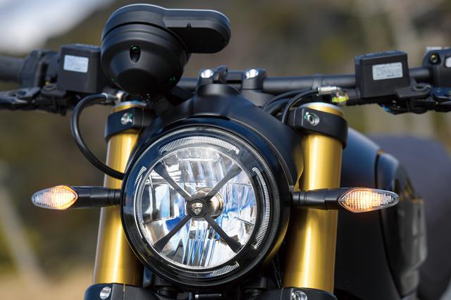 画像: かつてのオフロードモデルが装備していたヘッドライトを保護するテープをモチーフに、LEDヘッドライト前面にブラックメタル製のX形状フレームを装着して、スクランブラーらしさを強くアピールしている。