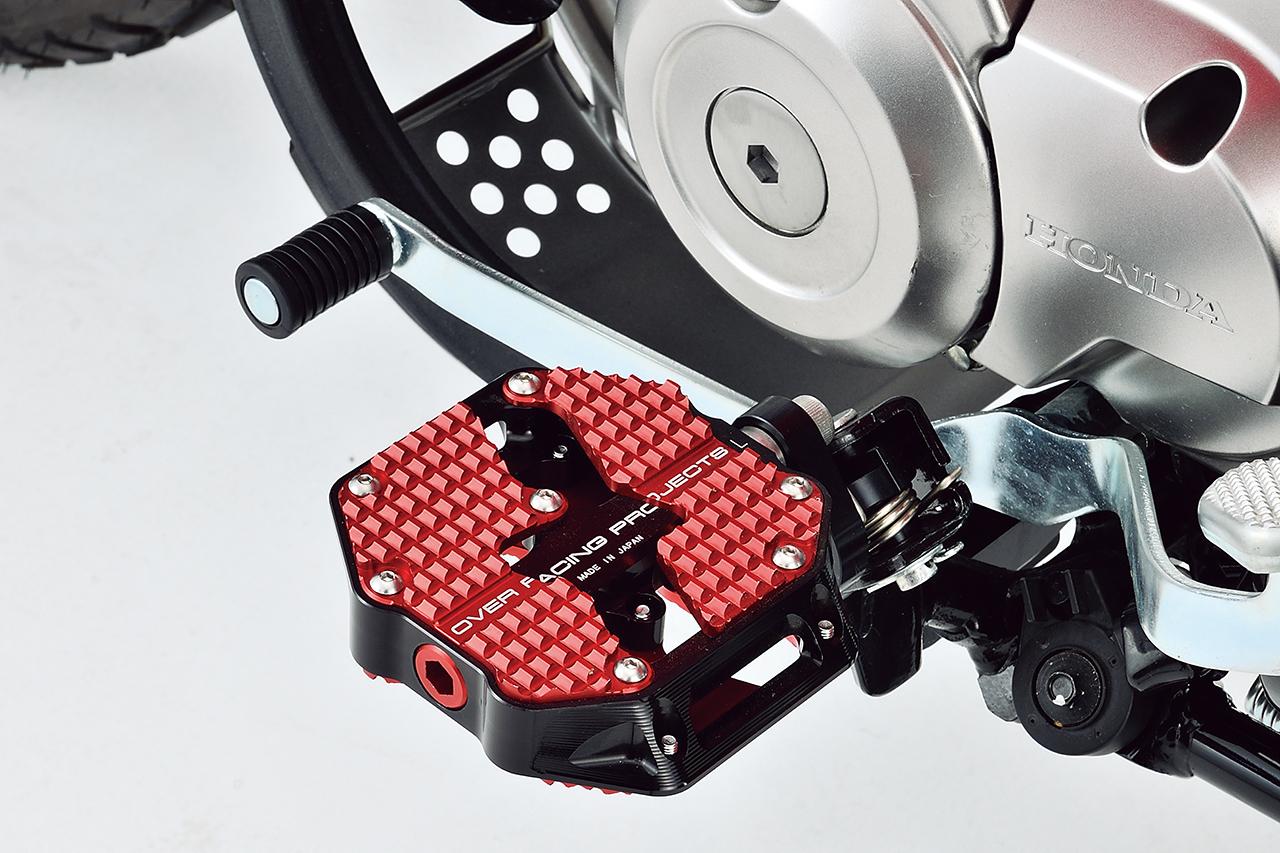 画像: ステップは2種類をラインアップ。まるで自転車のようなフラットペダル(税込8万3050円)はペダル自体が回転することで、長時間のライディングを快適に。カラーはブロンズ/レッドとブラック/レッドの2色を用意。