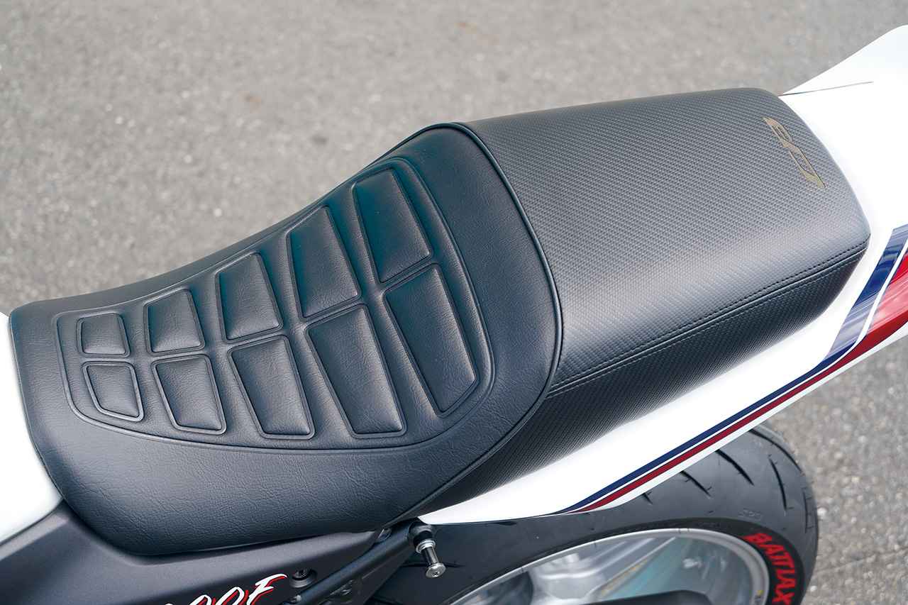 画像: アンコ抜きが施されたシートは、足つき性と実用性がさらに向上。往年のスーパーバイク風の段付きスタイルにしながら、タンデムシート部のレザーをカーボン調に変更。