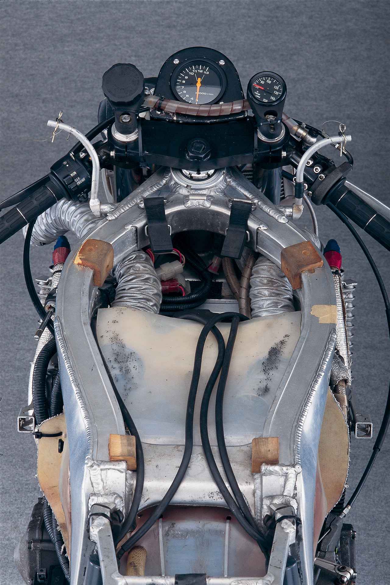 画像: ▲フロントフォークのブラケットや小物パーツにもRGV-Γのパーツが多用され、ベース車両よりも格段に太くされたフレームのメインチューブが、この車体がレーサーとして特別な成り立ちであることを物語っている。