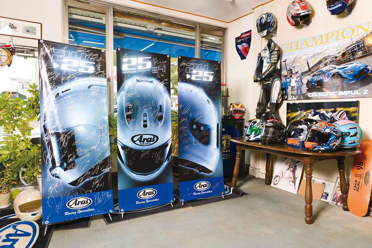 画像: ▲本社の来客スペースに展示されているフラッグには、アライヘルメットを使用するライダー&ドライバーのサインがびっしり。