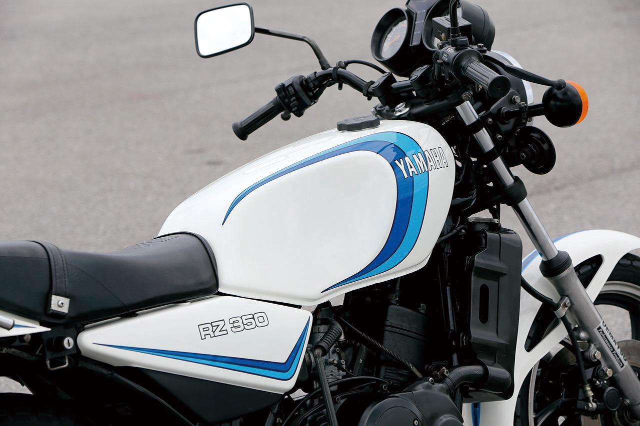 画像: ▲1981年登場のRZ350に採用された、ソノートヤマハレーシング由来のホワイト地にブルーラインを配した“ゴロワーズカラー”は、RZ250との差別化を図るために用意された。