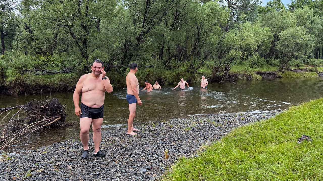 画像: キャンプサイトを流れる川で泳ぐスタッフとメンバー。水は超冷たい!